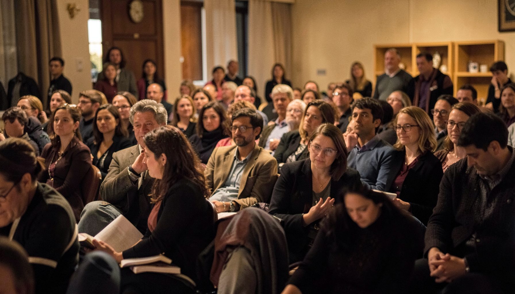 Audience at a literary gathering, warm indoor lighting