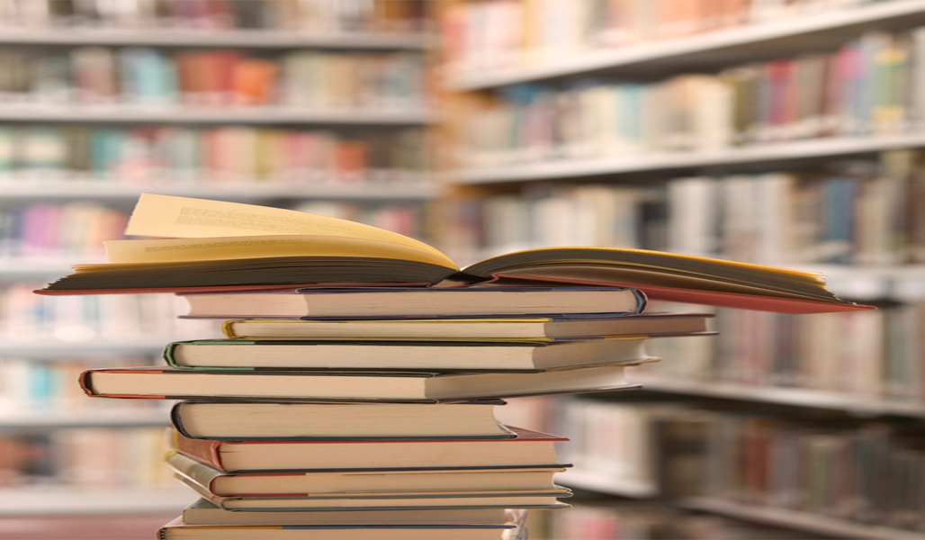 Warm library shelves with stacked books and an open volume, rich brown and amber tones