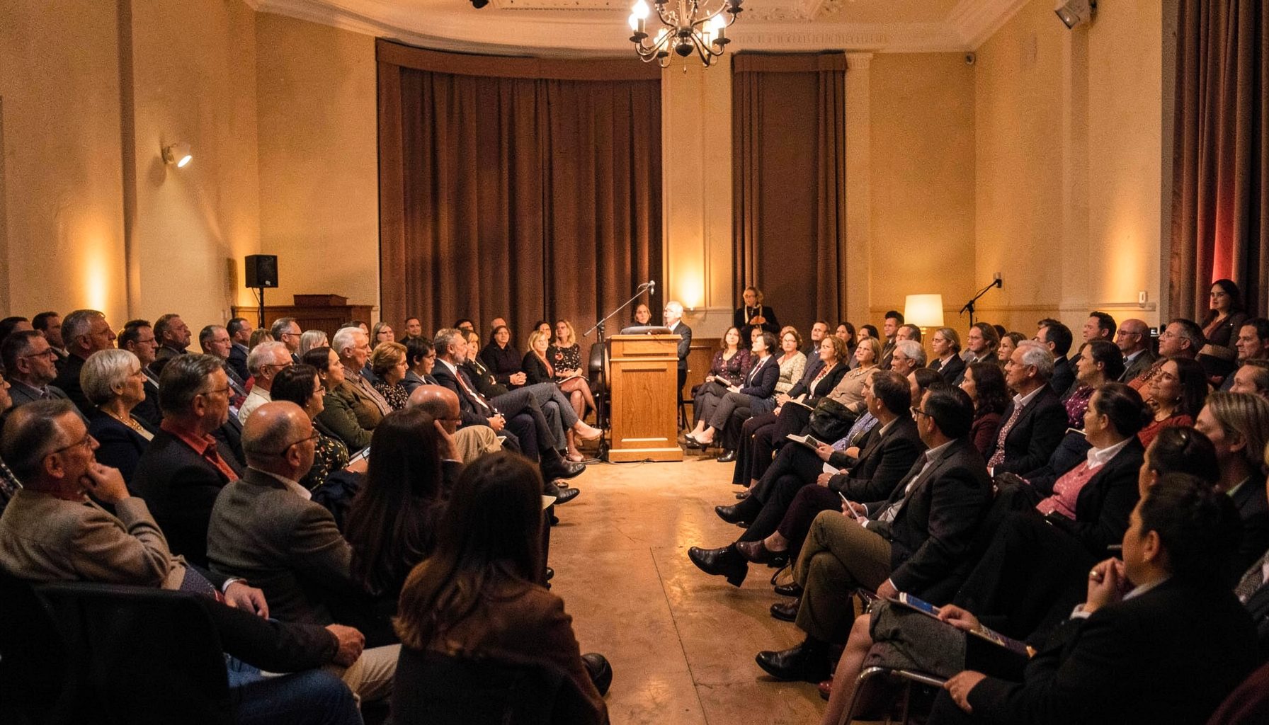 Literary gathering with podium and audience in warm hall lighting, cultural event